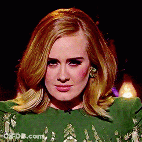 A Woman In A Green Dress Is Looking At The Camera GIF
