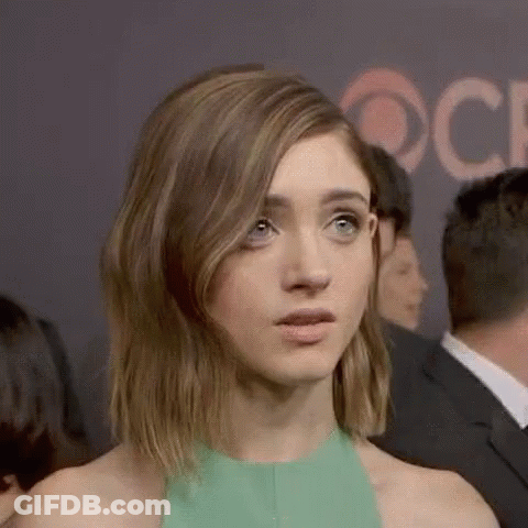 A Woman In A Green Dress Is Making A Funny Face While Standing In A Crowd Of People . GIF