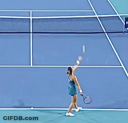 A Woman In A Green Dress Is Playing Tennis On A Court GIF
