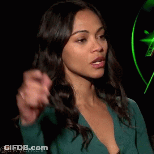 A Woman In A Green Dress Is Pointing Her Finger At Something . GIF