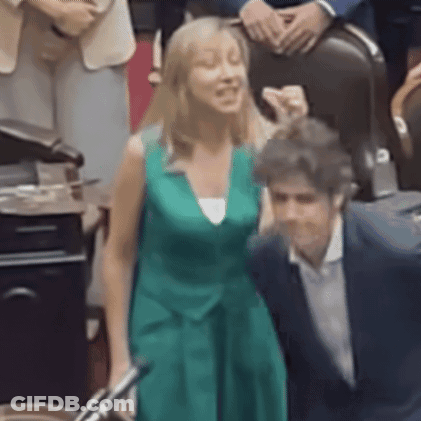 A Woman In A Green Dress Is Posing For A Picture With A Man In A Suit GIF