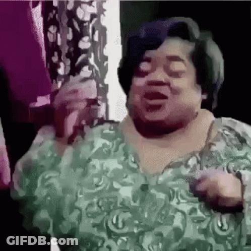 A Woman In A Green Dress Is Singing Into A Microphone And Dancing . GIF