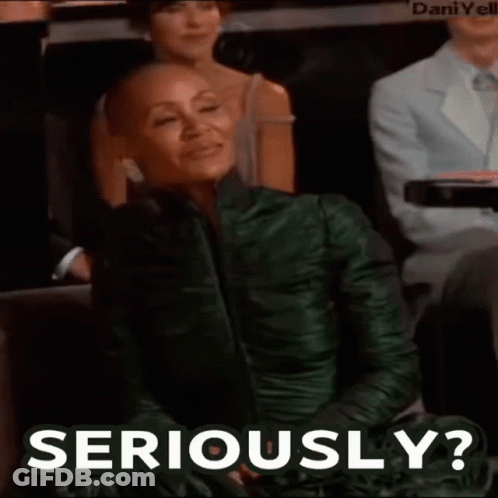 A Woman In A Green Dress Is Sitting In A Audience And Says Seriously . GIF