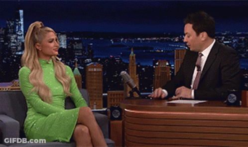 A Woman In A Green Dress Is Sitting In Front Of A Man In A Suit GIF