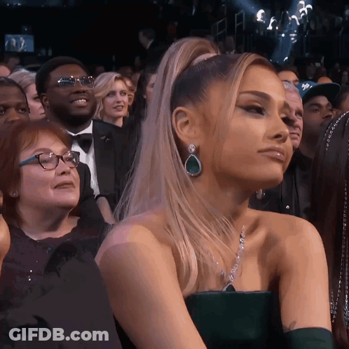 A Woman In A Green Dress Is Sitting In The Audience GIF