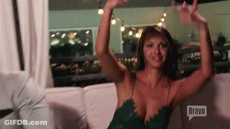 A Woman In A Green Dress Is Sitting On A Couch With Her Arms Outstretched . GIF