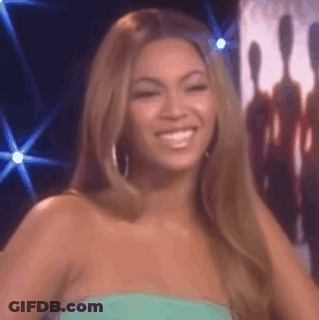 A Woman In A Green Dress Is Smiling And Looking At The Camera On A Stage . GIF