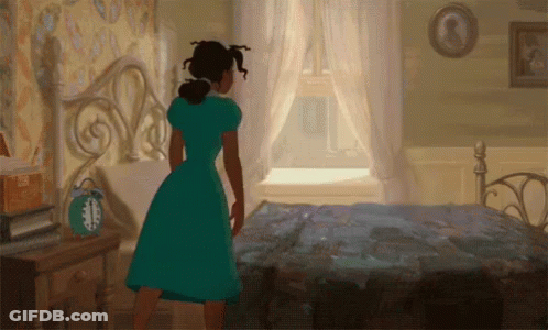 A Woman In A Green Dress Is Standing In Front Of A Bed In A Bedroom GIF