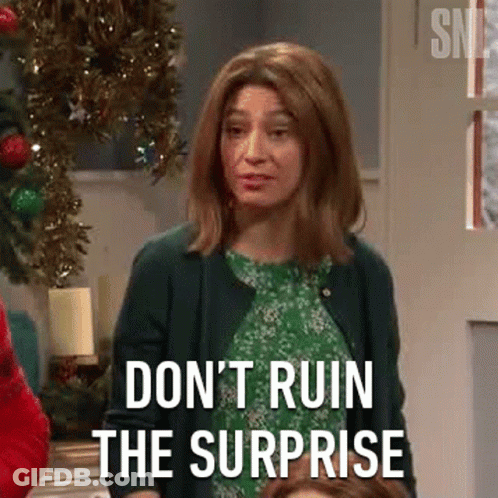 A Woman In A Green Dress Is Standing In Front Of A Christmas Tree And Saying `` Don 'T Ruin The Surprise '' . GIF
