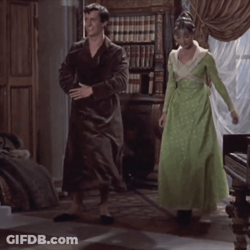 Woman In Green Dress Next To Man In Black Robe GIF