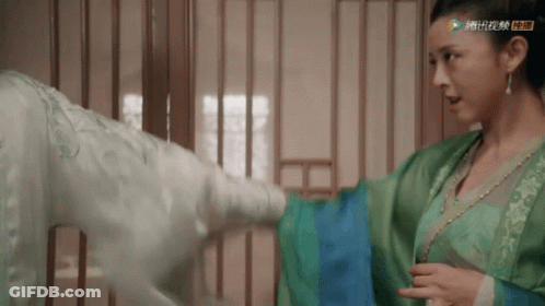 A Woman In A Green Dress Is Standing Next To A Man GIF