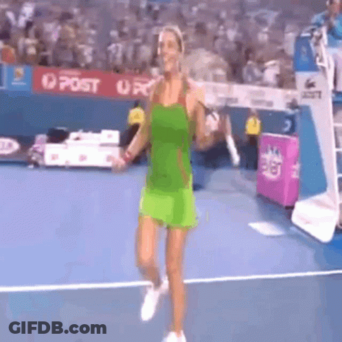 A Woman In A Green Dress Is Walking On A Tennis Court . GIF