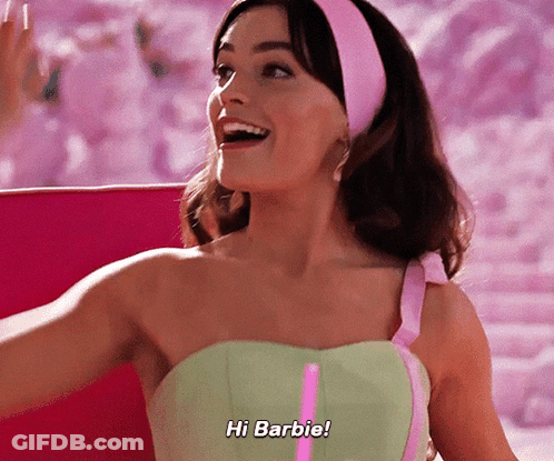 A Woman In A Green Dress Says Hi Barbie In A Pink Headband GIF