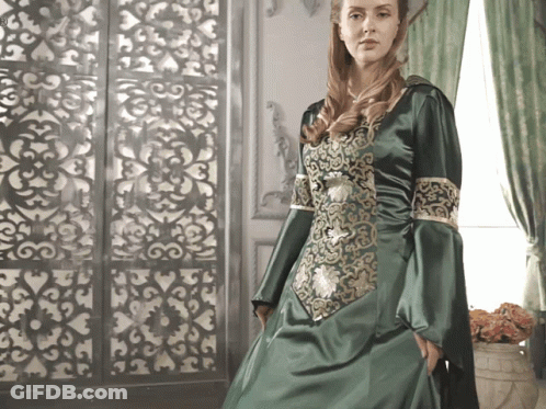 A Woman In A Green Dress With Gold Embroidery GIF