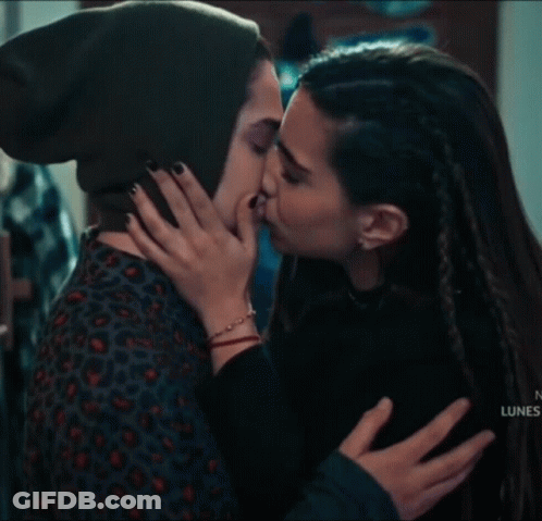 A Woman In A Green Hat Is Kissing Another Woman On The Forehead . GIF