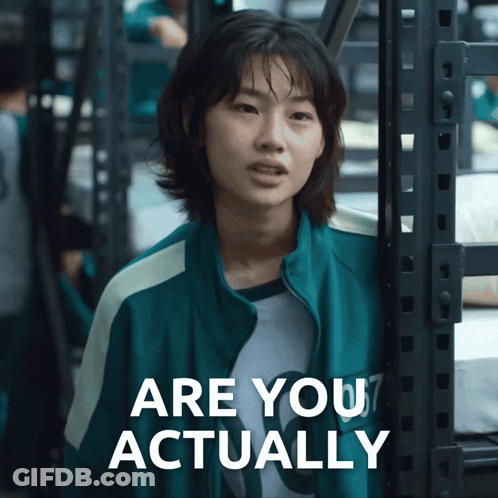 A Woman In A Green Jacket Is Standing Next To A Sign That Says Are You Actually GIF