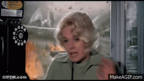 A Woman In A Green Jacket Is Talking On A Pay Phone GIF