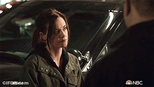 A Woman In A Green Jacket Is Talking To A Man In A Black Shirt In Front Of A Car That Says Nbc GIF