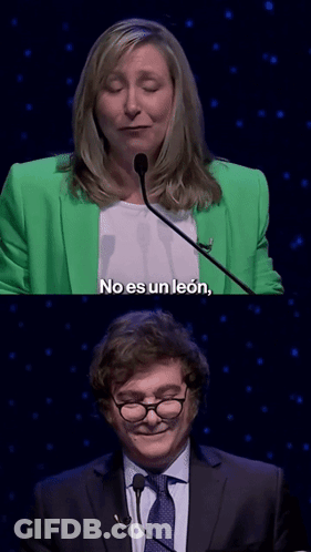A Woman In A Green Jacket Says No Es Un Leon Next To A Man GIF