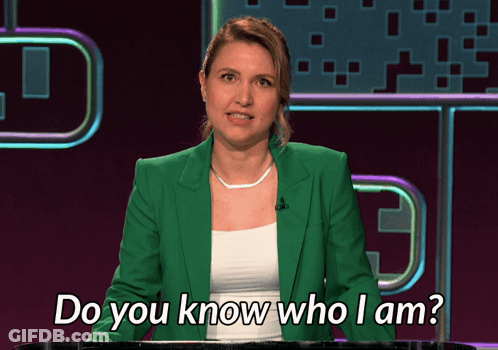 A Woman In A Green Jacket Stands Behind A Podium And Says Do You Know Who I Am GIF