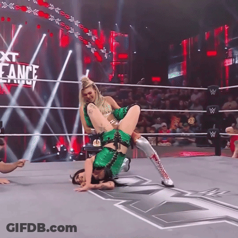 A Woman In A Green Outfit Is Doing A Flip In A Wrestling Ring With The Words Next Eance Behind Her GIF