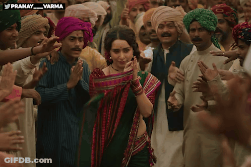 A Woman In A Green Saree Is Surrounded By A Crowd Of People With The Words Pranay Varma Above Her GIF