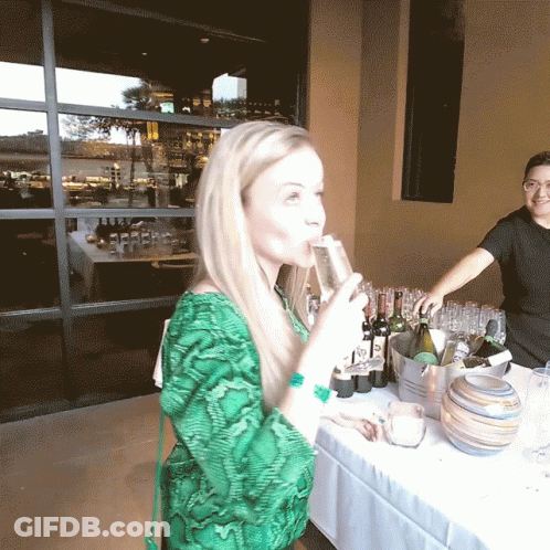 A Woman In A Green Shirt Drinks From A Glass GIF