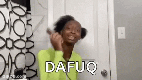 A Woman In A Green Shirt Is Brushing Her Hair In Front Of A Mirror . GIF