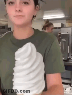 A Woman In A Green Shirt Is Holding A Giant Ice Cream Cone GIF