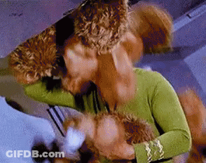 A Woman In A Green Shirt Is Holding A Stuffed Animal And Kissing It . GIF