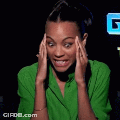 A Woman In A Green Shirt Is Holding Her Head In Pain GIF