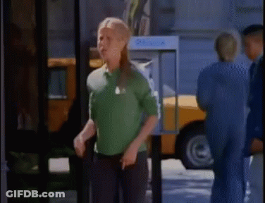 A Woman In A Green Shirt Is Standing In Front Of A Pay Phone Booth GIF