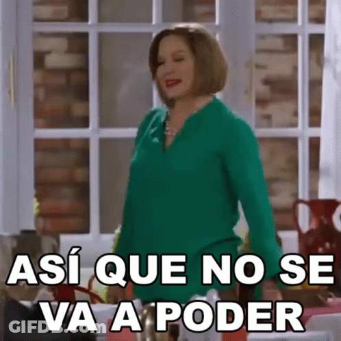 A Woman In A Green Shirt Is Standing In Front Of A Window And Making A Funny Face . GIF