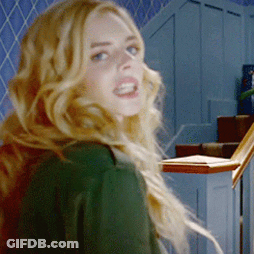 A Woman In A Green Shirt Is Standing In Front Of Stairs GIF