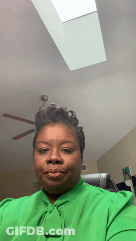 A Woman In A Green Shirt Is Taking A Selfie GIF