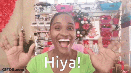 A Woman In A Green Shirt Says Hiya With Her Hands Up GIF