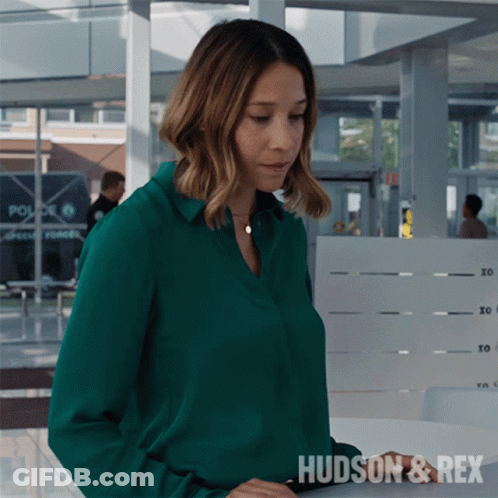 A Woman In A Green Shirt With The Word Hudson & Rex On The Bottom GIF