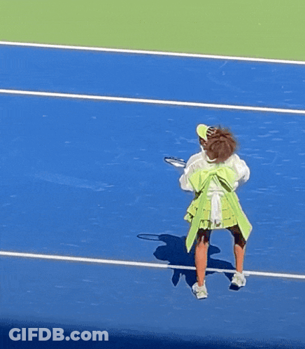 A Woman In A Green Skirt Is Holding A Tennis Racquet On A Tennis Court GIF