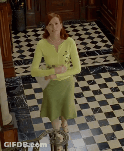 A Woman In A Green Skirt Is Standing On A Checkered Tile Floor GIF