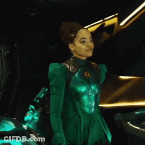 A Woman In A Green Suit Is Standing Next To A Car GIF