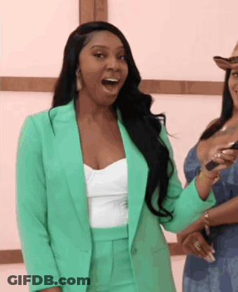 A Woman In A Green Suit Is Standing Next To Another Woman With Her Mouth Open GIF
