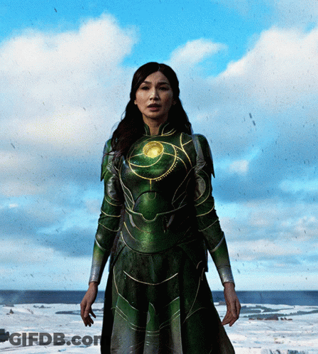 A Woman In A Green Superhero Costume Stands In The Snow GIF