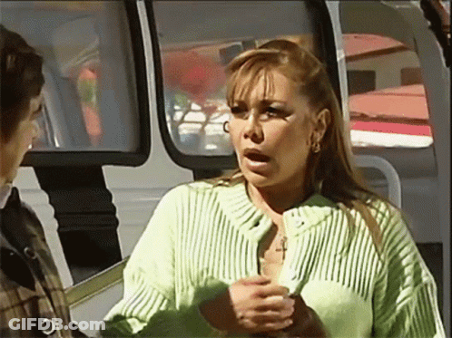 A Woman In A Green Sweater With A Cross On Her Chest GIF