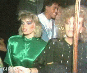A Woman In A Green Top Is Standing Next To Another Woman In A Black Top GIF