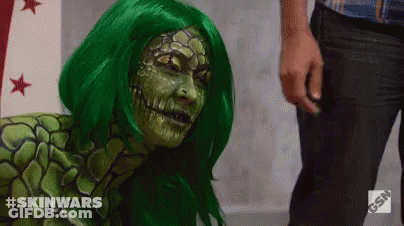 A Woman In A Green Wig Is Standing Next To A Man In Black Pants . GIF