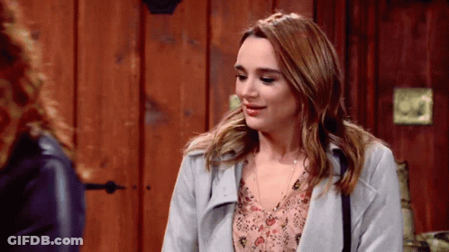 A Woman In A Grey Coat Is Talking To Another Woman GIF
