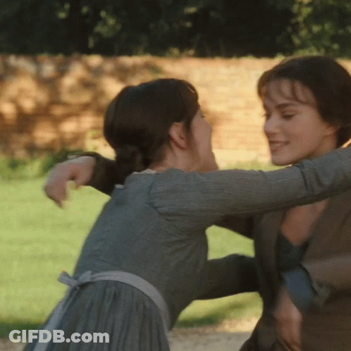 A Woman In A Grey Dress Is Hugging Another Woman In A Brown Jacket GIF