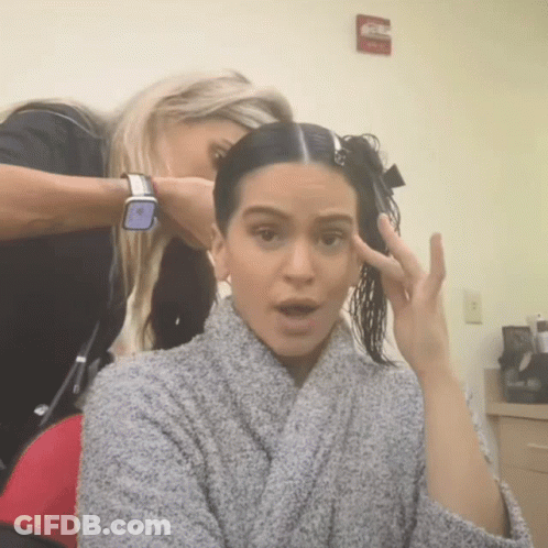 A Woman In A Grey Robe Is Getting Her Hair Done GIF