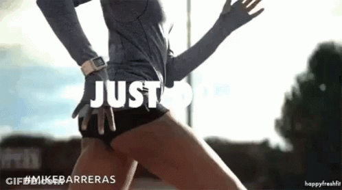 A Woman In A Grey Shirt And Black Shorts Is Running With The Words Just Do It Above Her GIF