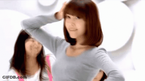 A Woman In A Grey Shirt Is Standing Next To Another Woman In A Pink Shirt GIF